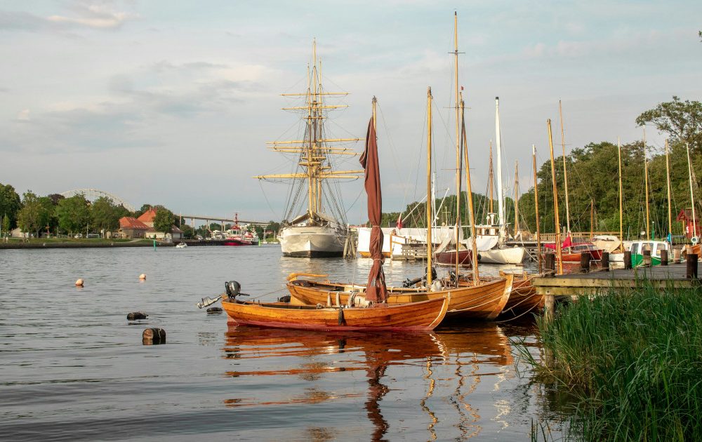 Foto der Kieler Förde mit Segeljollen und einem großen Segelschiff